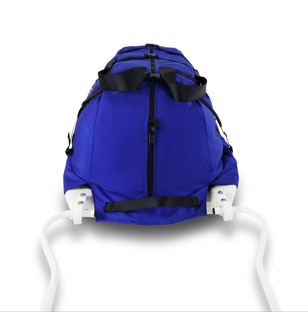 A Royal Blue snowmobile Sled Pulk cargo bag with black straps and a white plastic base, shown on a white studio background. With a tag labeled 'Wilderness Engineering'.