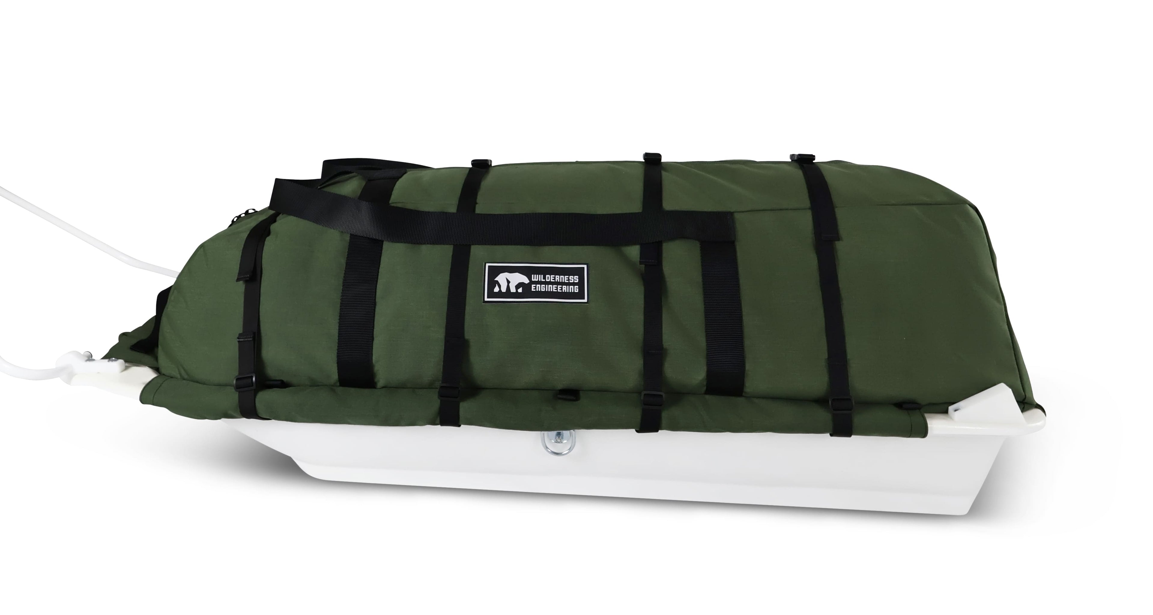 A Olive Green snowmobile pulk sled cargo bag with black straps and a white plastic sled base, shown on a clean white background. A black label on the front displays the brand 'Wilderness Engineering'.